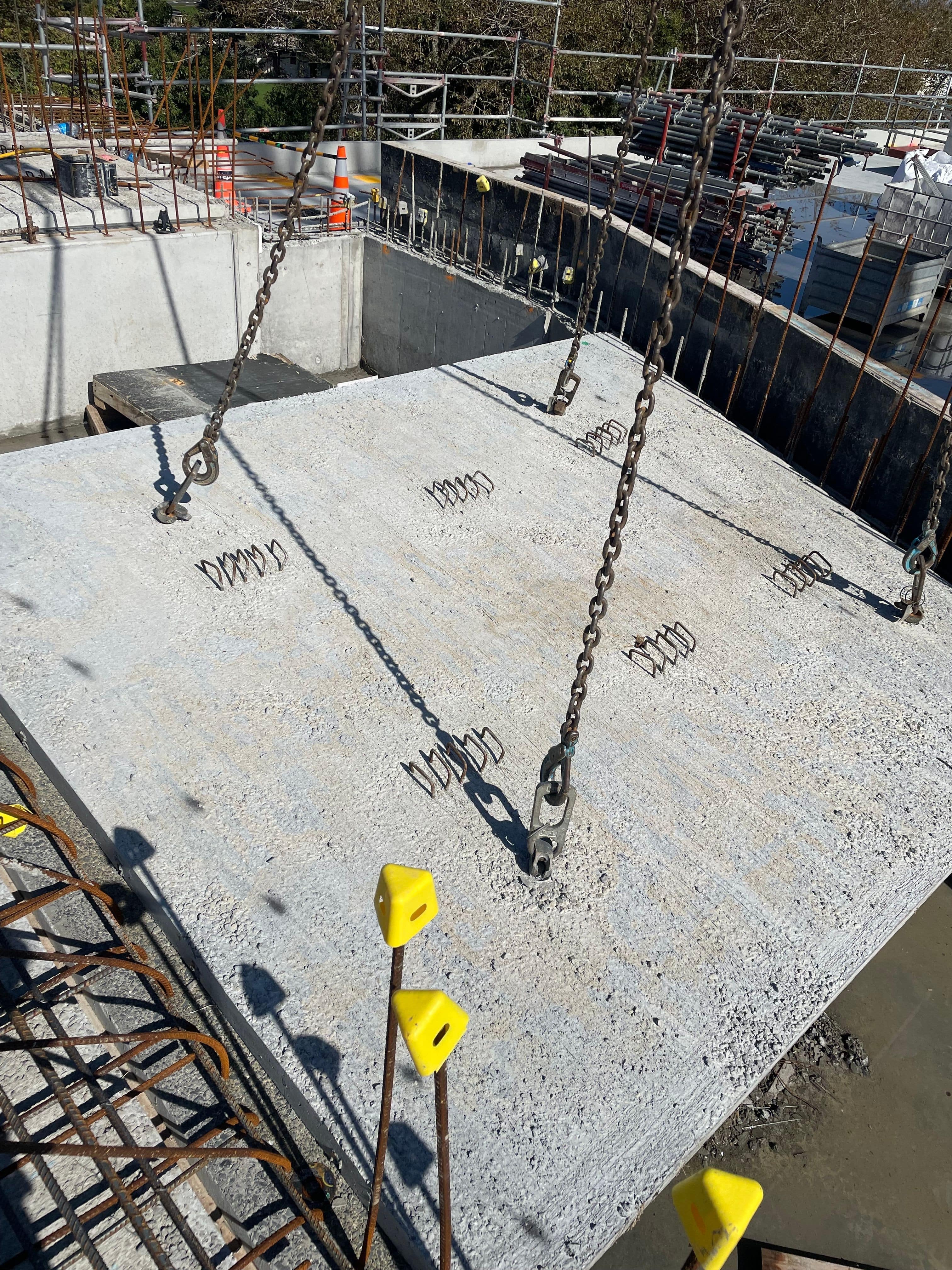 Chain rigging hardware on precast concrete, showing yellow shackles and lifting attachments